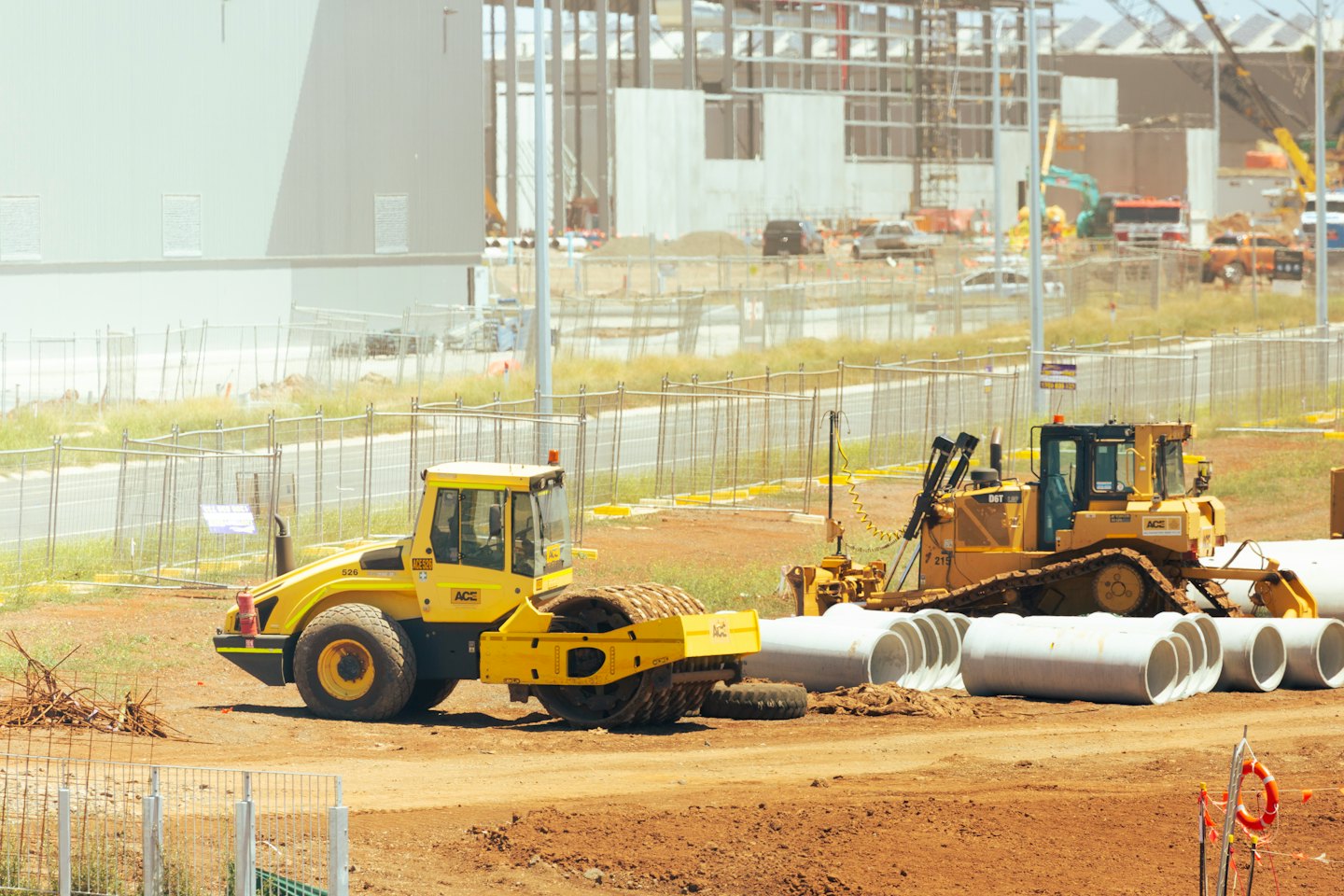 Macchine edili gialle e tubi in un cantiere.