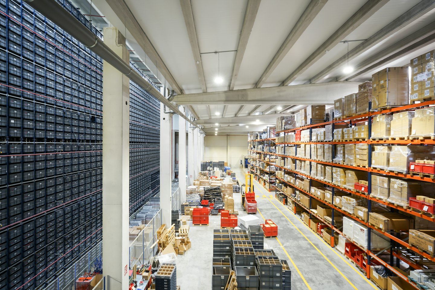 Un vasto magazzino industriale con scaffali pieni di contenitori e scatole.