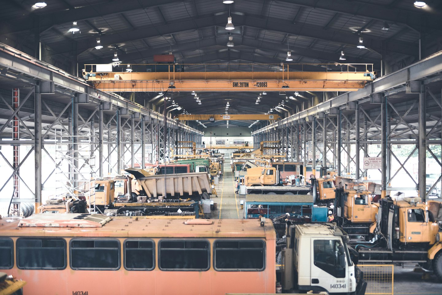 Un grande magazzino industriale pieno di macchinari pesanti e gru gialle.