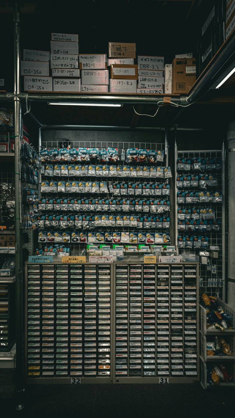 Piccole parti elettroniche organizzate in sacchetti di plastica su una griglia a muro.